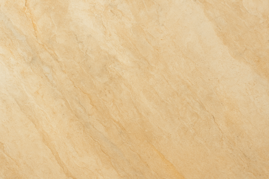 Close-up view of a beige natural stone surface with soft veining and warm earthy tones.